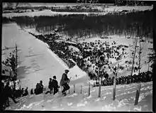 Photographie en noir et blanc d'un tremplin de saut à ski vu en plongée.