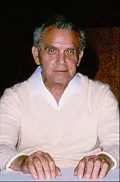 photographie en couleur d'un homme âgé assis devant une table