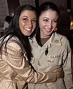 Miss New York USA 2004, Jaclyn Nesheiwat (en) (à gauche) rend visite aux troupes américaines en Irak en mars 2004. À Bagdad, elle rencontre sa sœur, le capitaine Julie Nesheiwat (à droite).