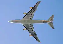 Vue de dessous d'un 747 en vol. Sous chacune des deux ailes se trouvent deux moteurs.