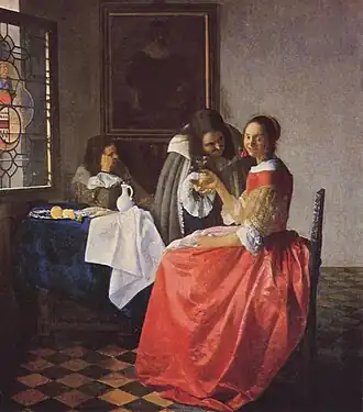 Portrait en pied de deux hommes et d'une femme, assise sur un siège, qui tourne le regard vers le spectateur.