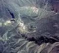 Photo couleur du cratère d'un volcan, recouvert de verdure, vue d'avion.