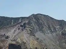 Photo couleur d'un effrondement sur les hauteurs d'un versant de montagne sous un ciel bleu.