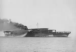 Le porte-avions japonais Akagi en juin 1927 dans sa configuration initiale pendant ses essais à la mer, avec deux  ponts d'envol superposés. La plateforme intermédiaire est celle de la passerelle et ne conduit pas aux hangars d'aviation. La cheminée est dirigée vers l'eau. La fumée noire au-dessus du pont est un essai d'écran de fumée