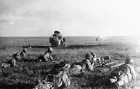 Photo en noir et blanc de soldats allongés tirant au fusil.