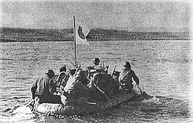 Photo en noir et blanc d'un groupe d'hommes pagayant sur un canot pneumatique.