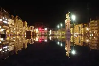 La place de Jaude de nuit et son reflet dans une fontaine