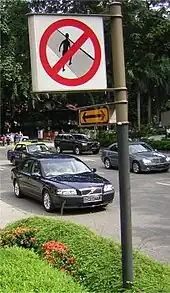 Panneau interdisant la traversée des piétons au bord d'une route fréquentée.