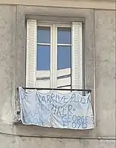 Photographie d'une banderole accrochée à la barrière d'une fenêtre, dans le 20e arrondissement de Paris. Il y est écrit "Je n'arrive plus à respirer. Adama Troaré. George Floyd.