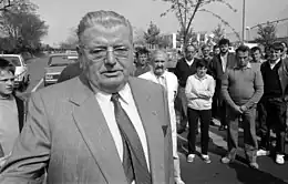 Photographie en noir et blanc d'un homme avec des lunettes, portant une cravate.