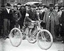 Photo d'un homme en tenue de ville sur un véhicule motorisé typé moto avec deux roues à l'arrière.