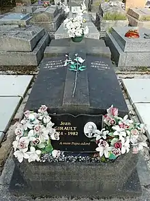 Photo en couleur centrée sur une tombe noire au milieu d'un cimetière.