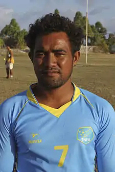 Photographie d'un homme, de face, en gros plan, avec un maillot bleu ciel et jaune, avec le numéro 7.