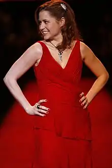 Photo d'une femme portant une robe rouge lors d'un défilé et regardant sur le côté gauche de la caméra.