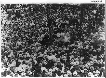 Photographie en noir et blanc d'une foule agglutinée autour d'un arbre et de Jesse Washington.