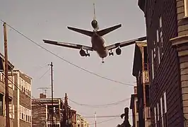 Un McDonnell Douglas DC-10 atterrissant sur l'aéroport Logan, au-dessus de la rue Neptune, à EastBoston. Les maisons bordant la voie seront rachetées par le Massachusetts Port Authority, et toutes démolies. Photo mai 1973.