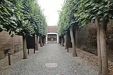 Photo d'une allée entourée d'arbres, au fond une cible sur un panneau en bois