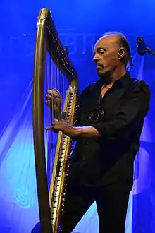Homme debout avec une harpe et sur fond bleu.