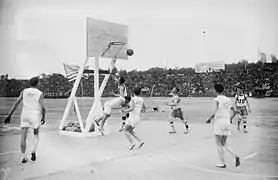 Deux équipes disputant un match de basket-ball sur un terrain en extérieur.
