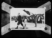 Un homme marchant alors que plusieurs autres tiennent des drapeaux.