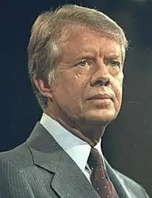 Photo en buste d'un homme de trois-quarts face, aux cheveux châtain, vêtu d'un costume