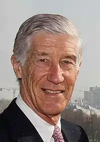 portrait photographique en couleurs d'un homme grisonnant et souriant, vu de face