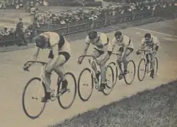 Photographie montrant quatre cyclistes à l'entraînement sur un vélodrome.