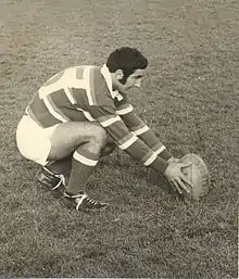 Photo noir et blanc d'un joueur en maillot rayé en train de placer le ballon au sol avant une pénalité