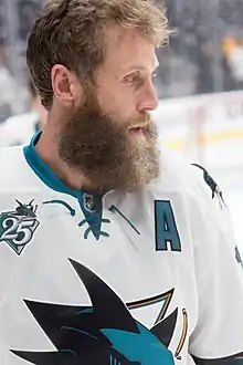 Photographie d'un joueur de hockey sur glace avec un maillot blanc et portant une barbe fournie