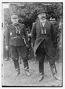 Le général en uniforme simple, le civil en veste et chapeau melon, les deux portant jumelles et bottes.