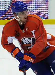 photographie d'un joueur de hockey avec un maillot orange et un casque bleu sur la tête