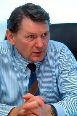 Photo d'un homme assis, portant une chemise bleue et une cravate