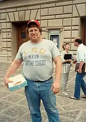 photo d'un homme souriant portant jean, tee-shirt et casquette.