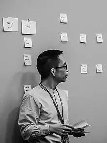 John Maeda devant un mur couvert de post-its