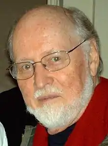 Homme blanc chauve avec des lunettes et une barbe blanche.