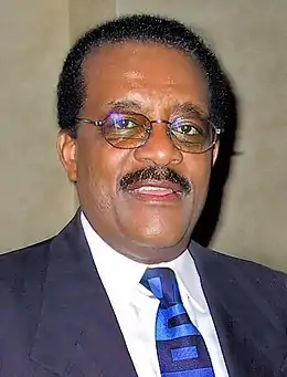 Portrait d'un homme noir en costume portant des lunettes de vue.