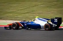 Photographie d'une monoplace de GP2, bleu foncé, blanche et orange, vue de profil.