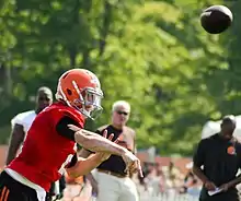 Photographie d'un joueur de football américain lançant un ballon.