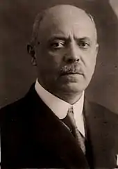 Portrait photographique en noir et blanc d'un homme souffrant de calvitie et portant la moustache.