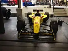 Monoplace de Formule 1 jaune, vue de face, dans un musée.