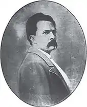 Photo ovale en noir et blanc montrant le portrait d'un homme moustachu