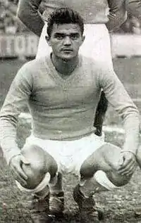 Photographie en noir et blanc d'un homme accroupi vu de face en tenue de footballeur avant un match.
