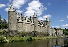 Château comportant trois tours, surplombant un canal.