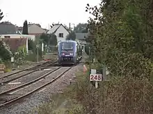 vue d'un train automoteur en circulation avec la mention « Loches » sur un panneau directionnel en bord de voie