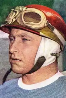 Photo colorisée en portrait rapproché de Juan Manuel Fangio arborant son casque de pilote.
