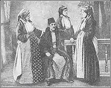 Photographie noir et blanc : un homme assis entouré de trois femmes.