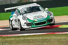 Photographie d'une Porsche Carrera blanche et verte, vue de trois-quarts.