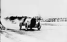 Photo de Jules Goux franchissant recevant à vive allure le drapeau à damier des 500 miles d'Indianapolis 1913.