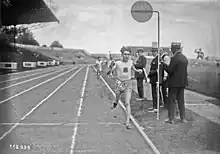 Photographie en noir et blanc d'un coureur à pied à l’arrivée de sa course dans un stade.