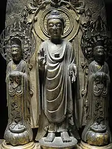 Photo couleur de trois statuettes en bronze doré représentant des icônes bouddhiques.